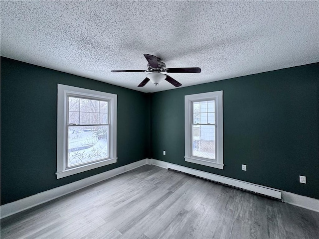 empty room featuring ceiling fan, a baseboard radiator, light hardwood / wood-style floors, and a textured ceiling