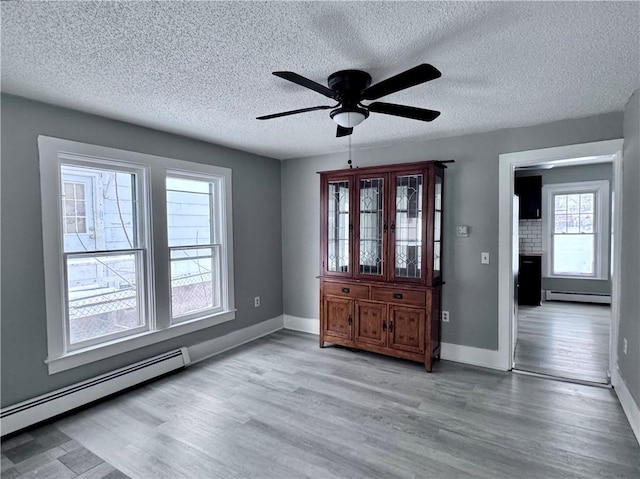 spare room featuring a baseboard radiator, light hardwood / wood-style floors, and ceiling fan