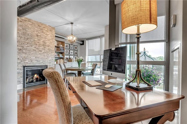 dining space with an inviting chandelier, plenty of natural light, a fireplace, and light hardwood / wood-style floors