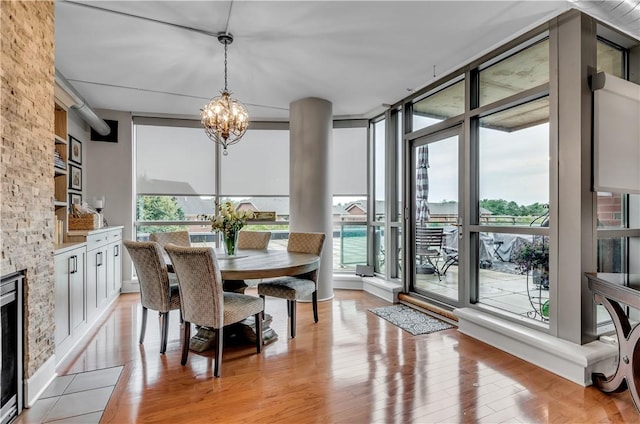 dining area featuring an inviting chandelier, a wealth of natural light, light hardwood / wood-style floors, and floor to ceiling windows