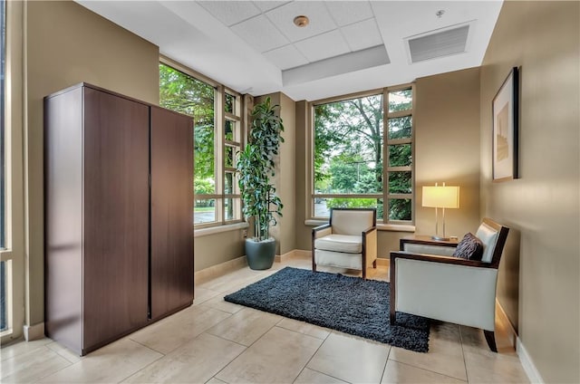 sitting room with light tile patterned flooring and a tray ceiling