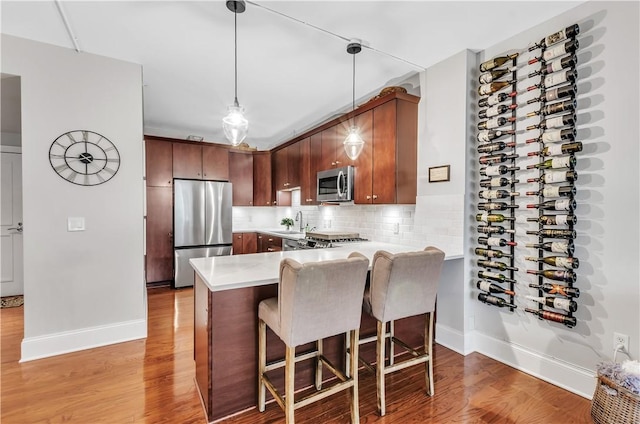 kitchen with decorative backsplash, light hardwood / wood-style flooring, stainless steel appliances, and kitchen peninsula