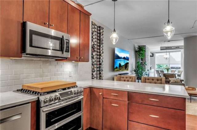 kitchen featuring pendant lighting, stainless steel appliances, kitchen peninsula, and backsplash