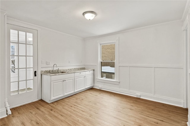 kitchen with white cabinetry, sink, ornamental molding, and light hardwood / wood-style flooring