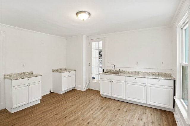 kitchen with sink, crown molding, white cabinets, and light wood-type flooring