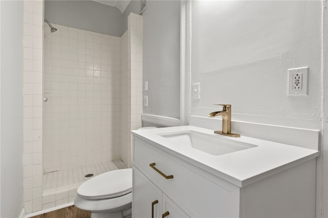 bathroom with vanity, wood-type flooring, tiled shower, and toilet