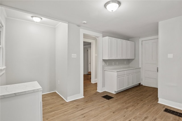 interior space with white cabinetry, ornamental molding, and light hardwood / wood-style floors