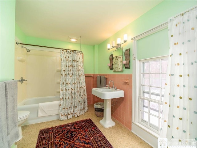 full bathroom featuring a healthy amount of sunlight, tile walls, shower / bathtub combination with curtain, and toilet