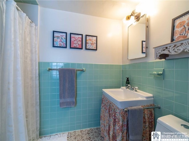 bathroom with tile walls, curtained shower, and toilet