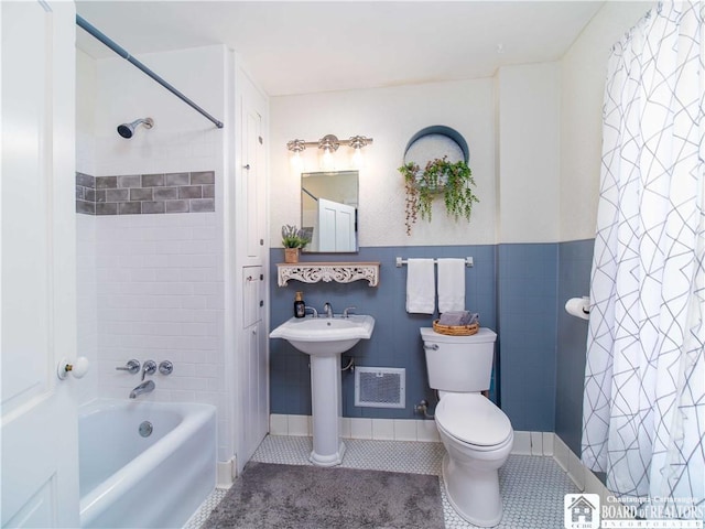 bathroom featuring tile patterned flooring, toilet, and shower / bathtub combination with curtain