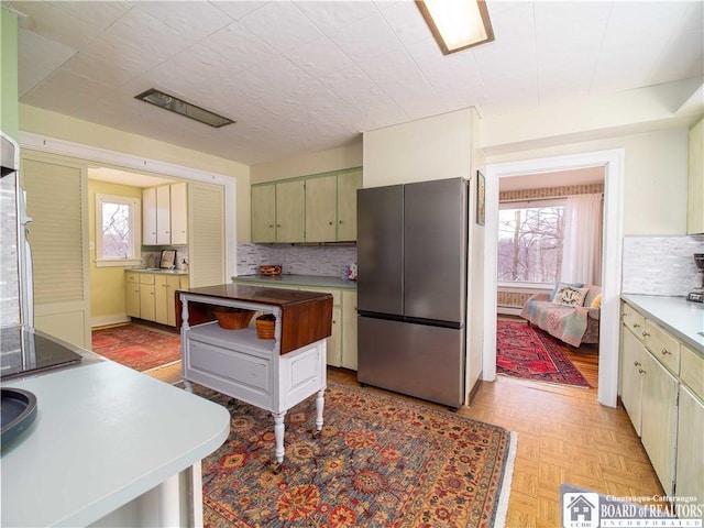 kitchen with a kitchen island, stainless steel fridge, decorative backsplash, and light parquet floors