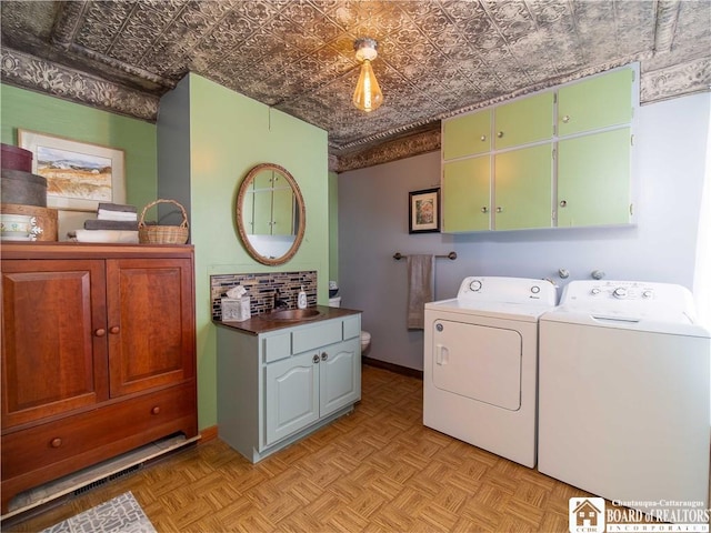 laundry room with cabinets, separate washer and dryer, sink, and light parquet floors