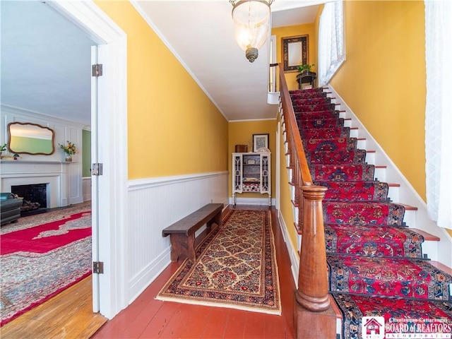 staircase with wood-type flooring, ornamental molding, and vaulted ceiling