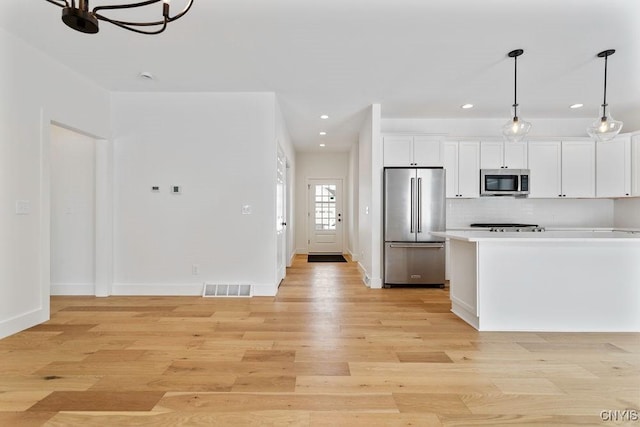 kitchen with stainless steel appliances, visible vents, white cabinetry, hanging light fixtures, and light countertops