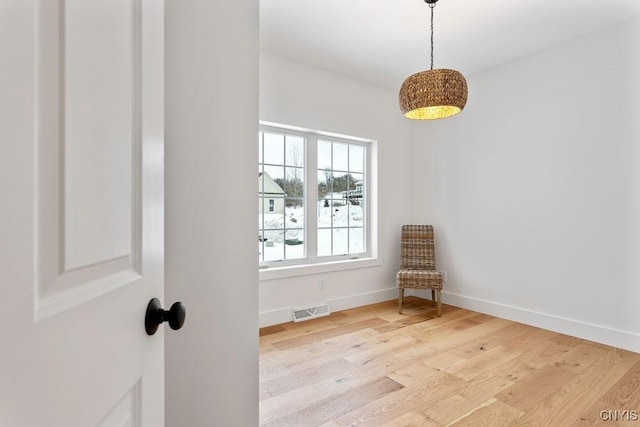 sitting room featuring light wood-style floors, visible vents, and baseboards