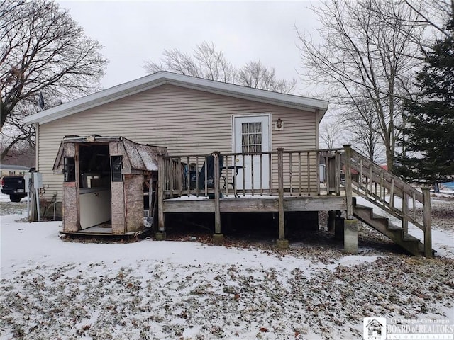 snow covered rear of property with a deck