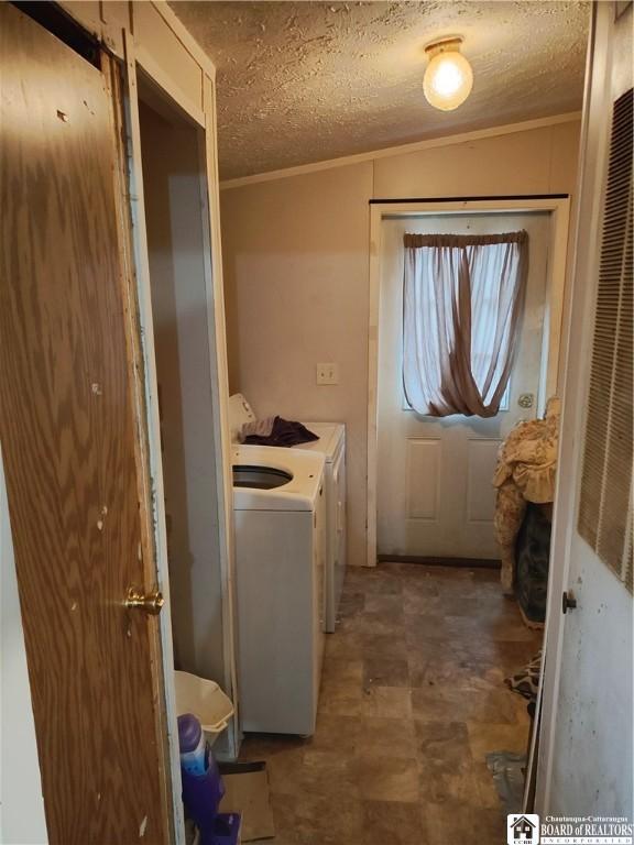 clothes washing area featuring ornamental molding, washer and dryer, and a textured ceiling