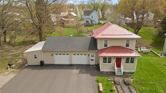 traditional-style home featuring a garage, a front lawn, aphalt driveway, and metal roof