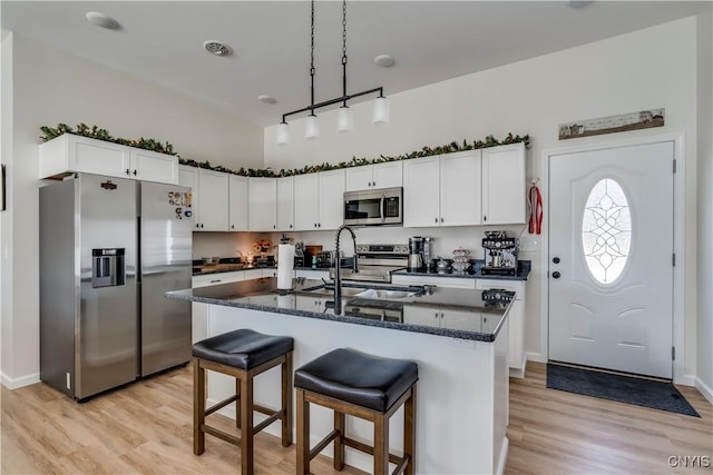 kitchen featuring a sink, light wood-style flooring, appliances with stainless steel finishes, and hanging light fixtures