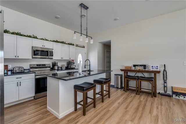 kitchen with a sink, white cabinets, stainless steel appliances, and light wood finished floors