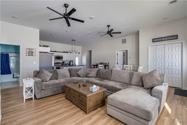 living area featuring a ceiling fan, visible vents, and light wood finished floors