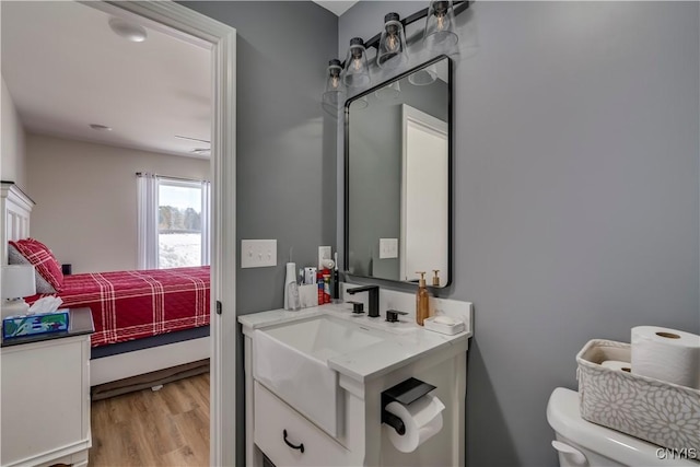 bathroom with vanity, connected bathroom, wood finished floors, and toilet