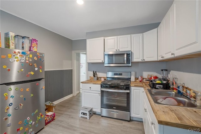 kitchen featuring wood counters, white cabinetry, sink, light hardwood / wood-style floors, and stainless steel appliances