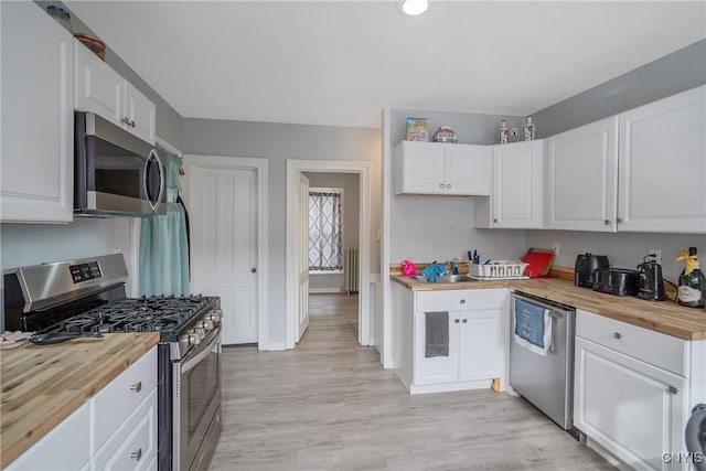 kitchen featuring white cabinetry, butcher block countertops, light hardwood / wood-style flooring, and appliances with stainless steel finishes