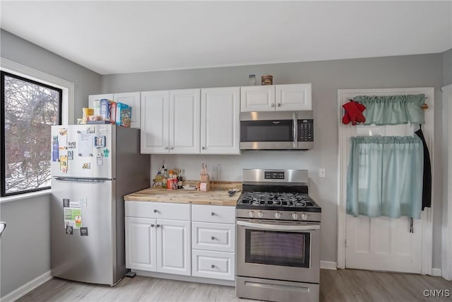 kitchen featuring stainless steel appliances, light wood-type flooring, and white cabinets