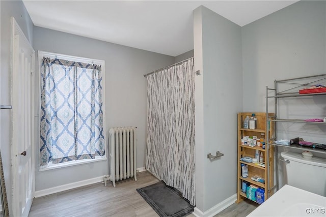 bathroom with hardwood / wood-style flooring, plenty of natural light, radiator, and toilet