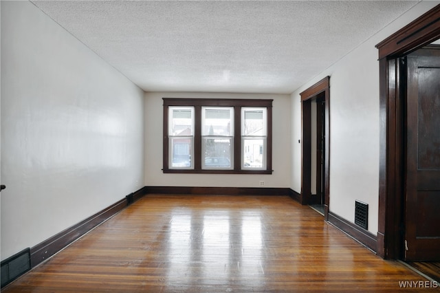 spare room with hardwood / wood-style floors and a textured ceiling