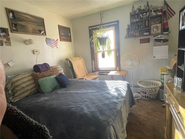 carpeted bedroom featuring a drop ceiling