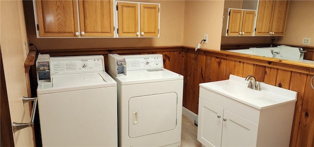 washroom with sink, wooden walls, and independent washer and dryer