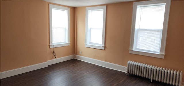 spare room featuring dark hardwood / wood-style flooring and radiator