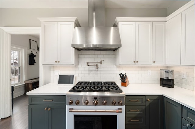 kitchen featuring white cabinets, decorative backsplash, wall chimney exhaust hood, and high end stove