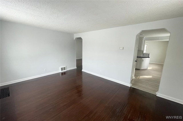 empty room with dark hardwood / wood-style floors and a textured ceiling