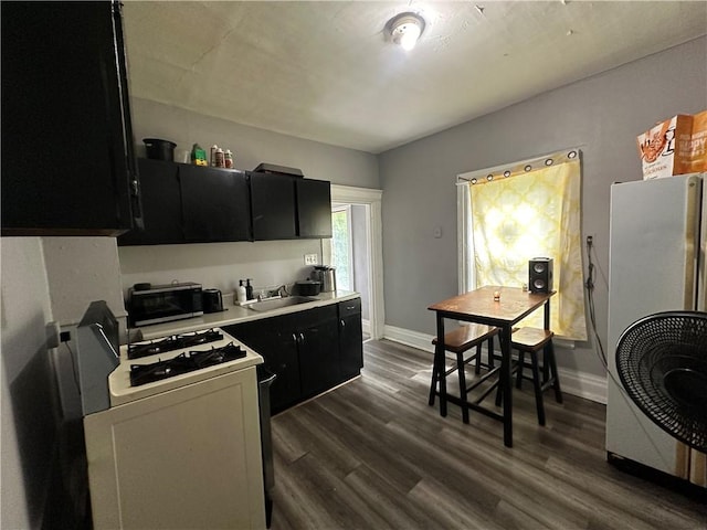 kitchen with sink, dark hardwood / wood-style floors, fridge, and white gas range oven