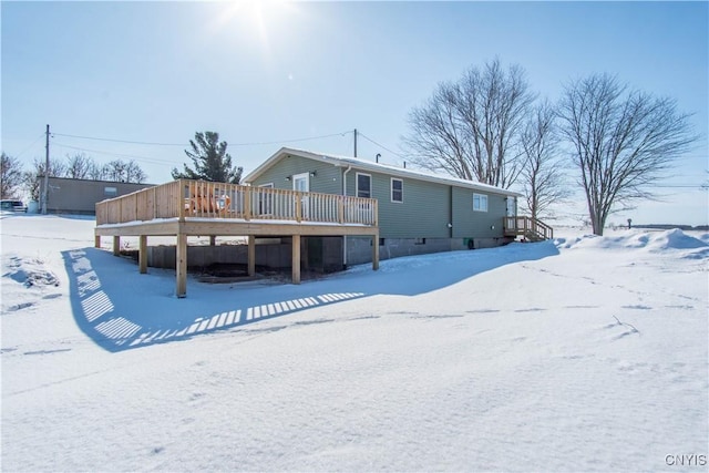 snow covered rear of property featuring a deck