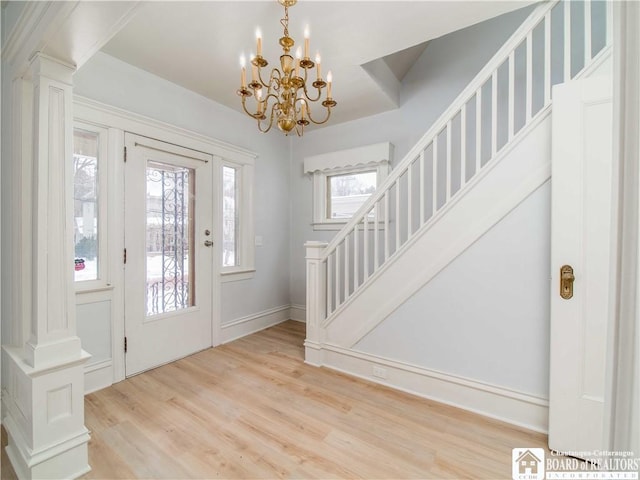 foyer featuring an inviting chandelier, light hardwood / wood-style flooring, and decorative columns