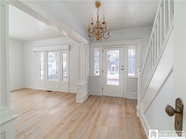 foyer entrance featuring ornate columns, an inviting chandelier, and light hardwood / wood-style flooring