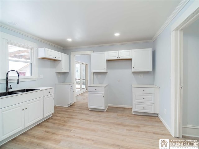 kitchen featuring sink, crown molding, white cabinetry, a wealth of natural light, and light hardwood / wood-style floors