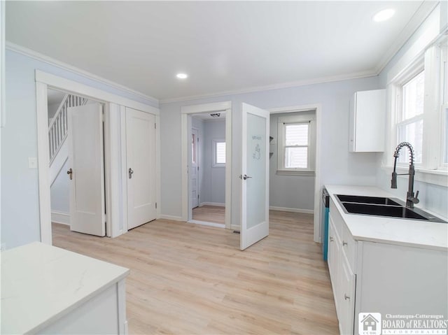 kitchen with white cabinetry, sink, and ornamental molding