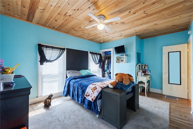 bedroom featuring ceiling fan, wood-type flooring, a spacious closet, wooden ceiling, and a closet