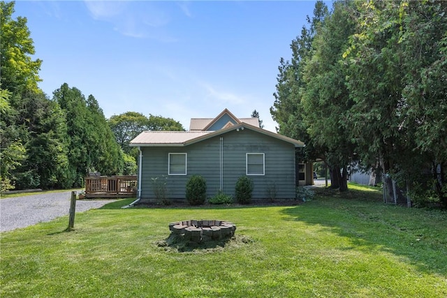 view of property exterior with a wooden deck, a yard, and an outdoor fire pit