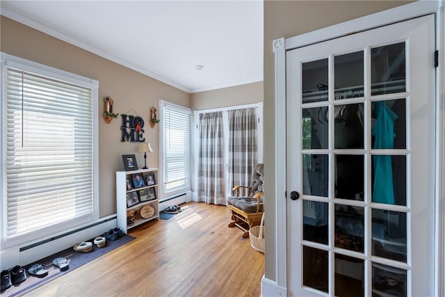 interior space with crown molding, baseboard heating, and hardwood / wood-style flooring