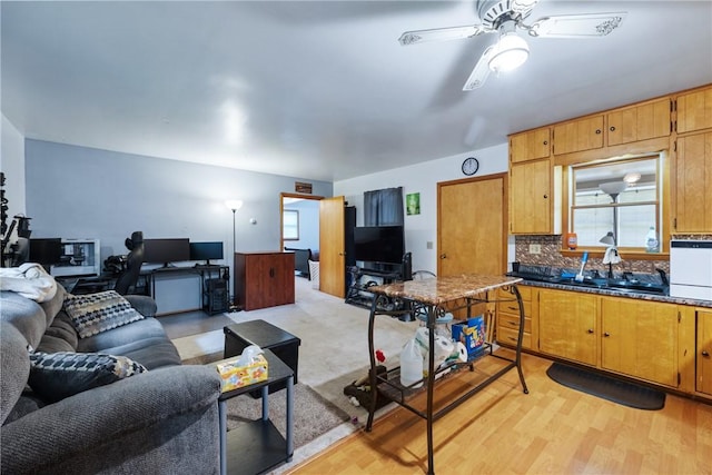 living room with sink, light hardwood / wood-style floors, and ceiling fan