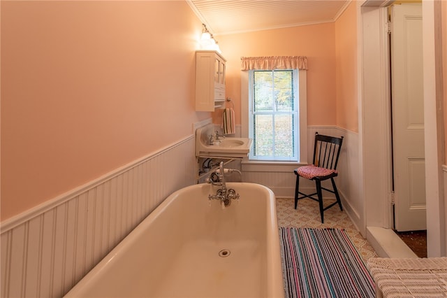 bathroom with crown molding, a tub, and sink