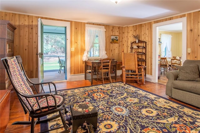 living area with hardwood / wood-style flooring, ornamental molding, and wood walls