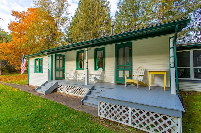 rear view of house featuring covered porch and a lawn