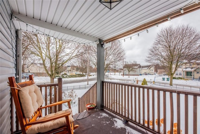 snow covered back of property featuring covered porch